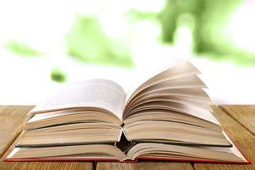 Three open books on wooden table on natural background
