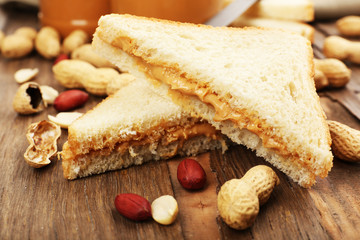 Bread slices with creamy peanut butter on wooden table