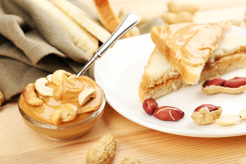 Bread slices with creamy peanut butter on wooden table