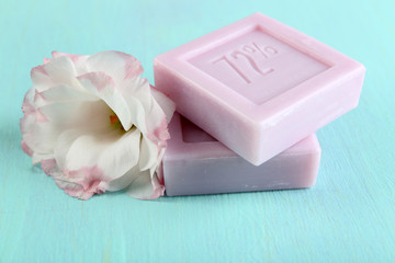 Bars of natural soap with fresh flowers on wooden background