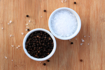 Coarse salt and black peppercorns in white ceramic bowls - 72061968