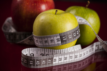 Apples with measuring tape over red background
