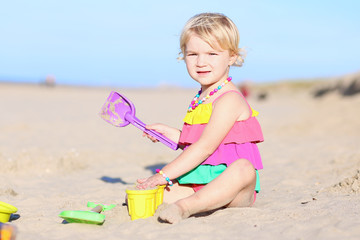 Cute toddler girl playing on the beach