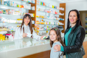 Pharmacist giving vitamins to child girl in pharmacy