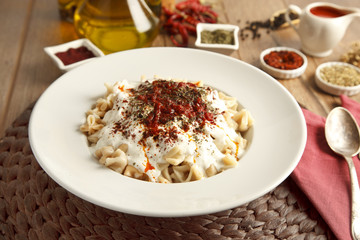 Turkish Manti manlama on plate with  tomatoes sauce, yogurt