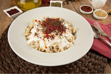 Turkish Manti manlama on plate with  tomatoes sauce, yogurt