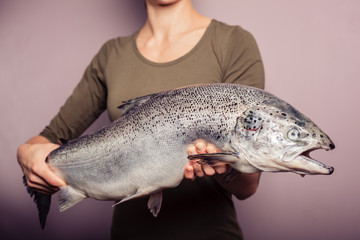 Young woman holding a big salmon