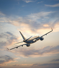 Fototapeta na wymiar Airplane flying above sunset