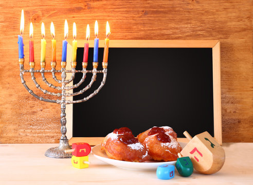 jewish holiday Hanukkah with menorah, doughnuts over wooden tabl