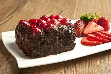 Piece of chocolate cake with icing and fresh berry