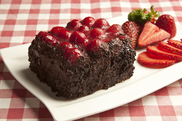 Piece of chocolate cake with icing and fresh berry