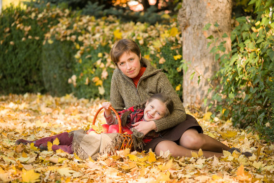 woman and little girl in autumn park with apple basket