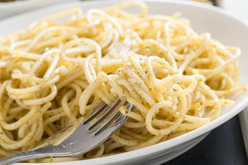 plate of spaghetti with pesto and cheese, close-up