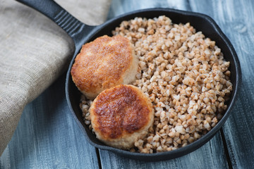 Close-up of boiled buckwheat with cutlets, high angle view