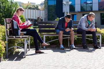 Boys using phones and girl learning