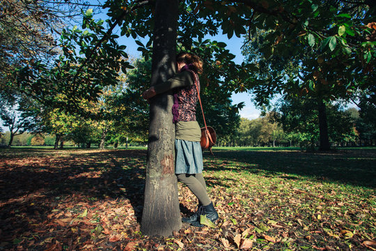 Young woman hugging tree in autumn