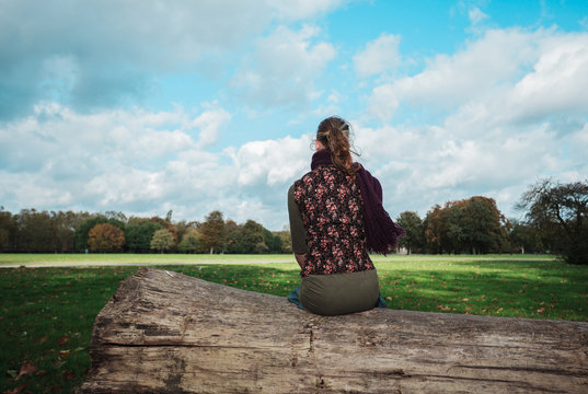 Woman sitting on a fallen tree in the park