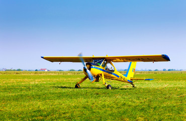 Fototapeta na wymiar Retro yellow airplane on a green grass field preparing to take o
