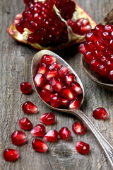 spoon with pomegranate seeds on a wooden background