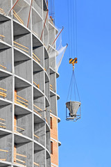 Fototapeta na wymiar Crane lifting concrete mixer container against blue sky