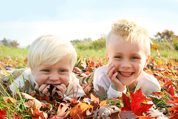 Two Happy Young Children Playing Outside in Fall Leaves
