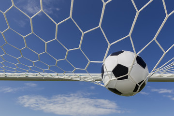 Naklejka premium Soccer football in Goal net with sky field.