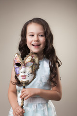 Cheerful little girl posing with carnival mask