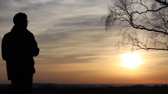 Mann mit Fernglas beim Sonnenuntergang