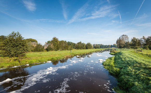 Big flocs of white colored foam on a river - Powered by Adobe