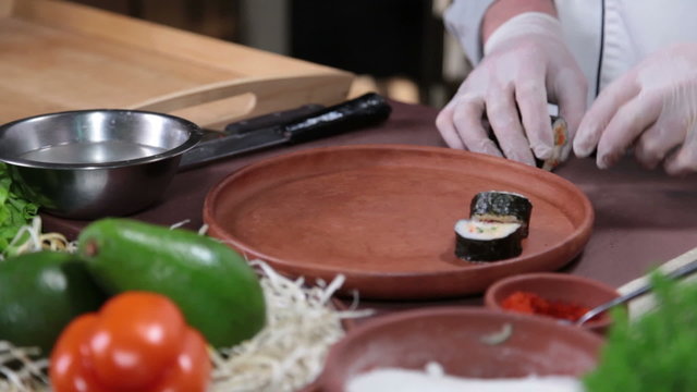 Cook serving delicious Japanese sushi rolls on a wooden plate