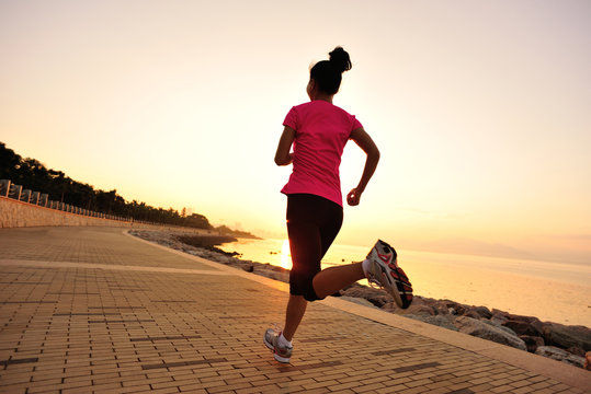 woman runner athlete running at sunrise seaside
