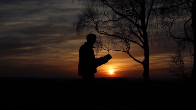 Mann orientiert sich mit einer Karte bei Sonnenuntergang
