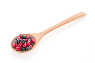 Pills drug on wooden spoon isolated on white background
