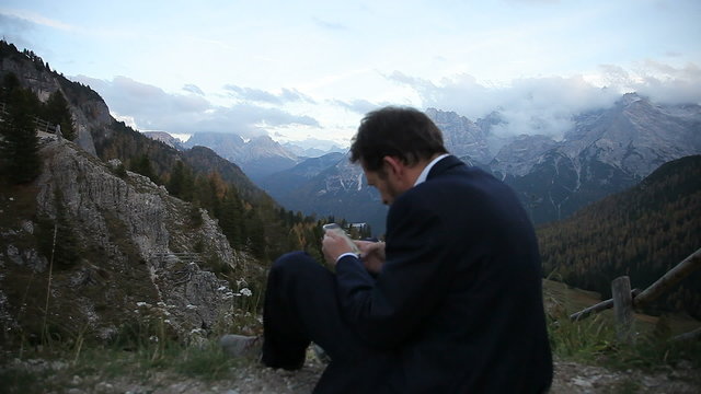 Business man taking picture of mountain landscape