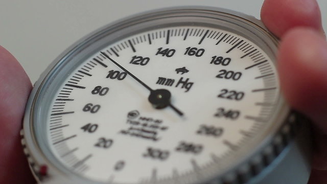Extreme close-up nurse measures blood pressure with sphygmometer