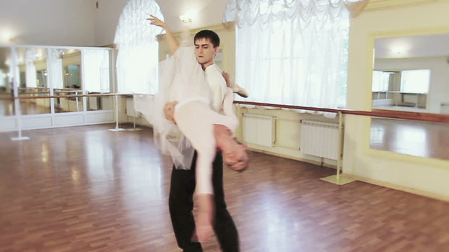 Young male holds ballerina on shoulder and twirls her around
