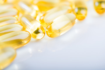 shiny yellow vitamin e fish oil capsule on white background