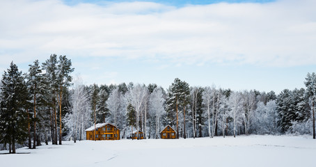 Fototapeta na wymiar Wooden houses in a nature area covered with snow.