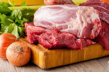 Tagli di carne bovina e suina cruda appoggiati sul tagliere