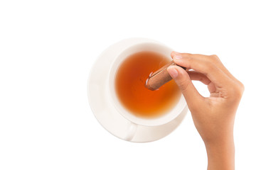 Female hand with a cup of tea and cinnamon stick