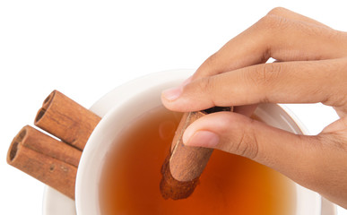 Female hand with a cup of tea and cinnamon stick