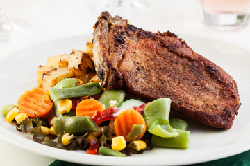 Fried pork with potatoes and vegetables salad