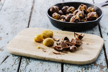 roasted chestnuts in the pan on a wooden surface