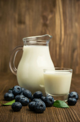 Obraz na płótnie Canvas milk in glass jug and blueberries