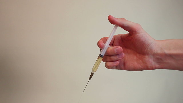 Close-up hand holding a syringe, doctor giving an injection