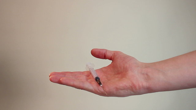 Hand offering syringe with dark substance, medicine, injection