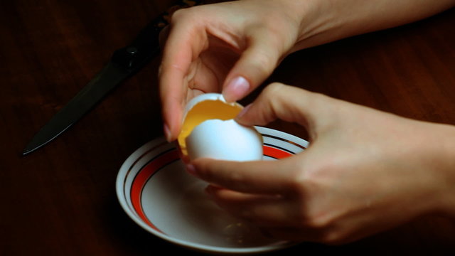 female hand separating yolk from egg white closeup