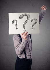 Businessman holding a paper with question marks in front of his
