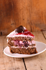 Piece of cake with chocolate heart on wooden background