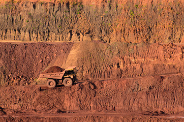 Loaded tip-truck going up along the open mine wall
